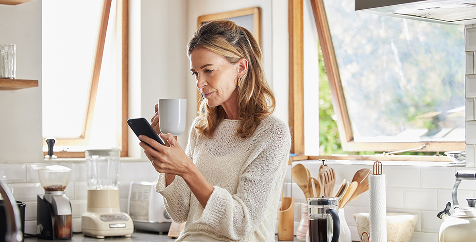 frau-in-küche-mit-smartphone-und-kaffee